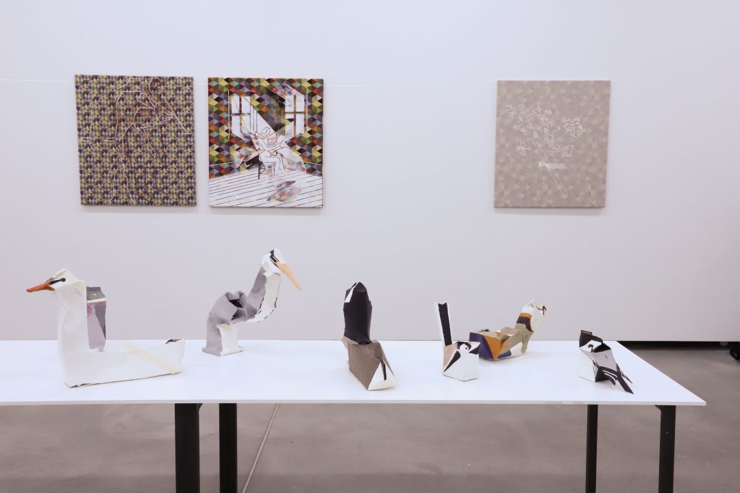 A series of waterfowl sculptures made from drinking containers covered in wax with paintings in the background. From Madeleine Kelly's exhibition, The first killing of the butterfly.